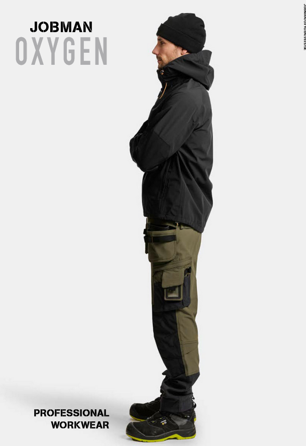 Person i JOBMAN OXYGEN-arbetskläder: svart mössa, huvad jacka, olivgrön-svarta byxor med fickor och förstärkningar, svarta skor med gula sulor. Bilden förmedlar hållbarhet, funktion och yrkesstil.
