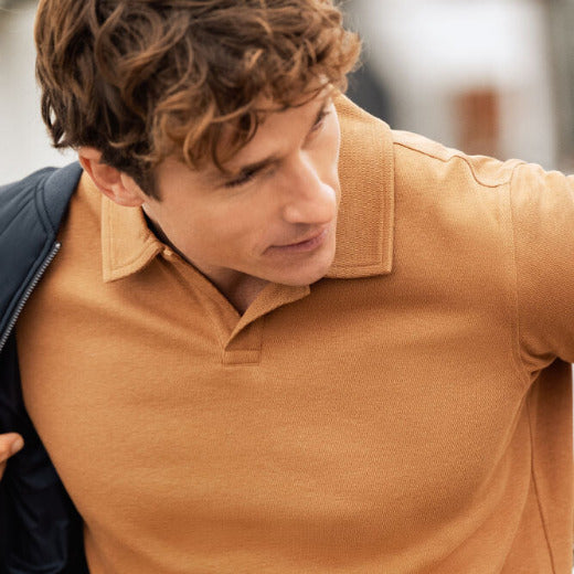 Närbild på person i beige pikétröja - bekväma arbetsplagg för både arbete och fritid